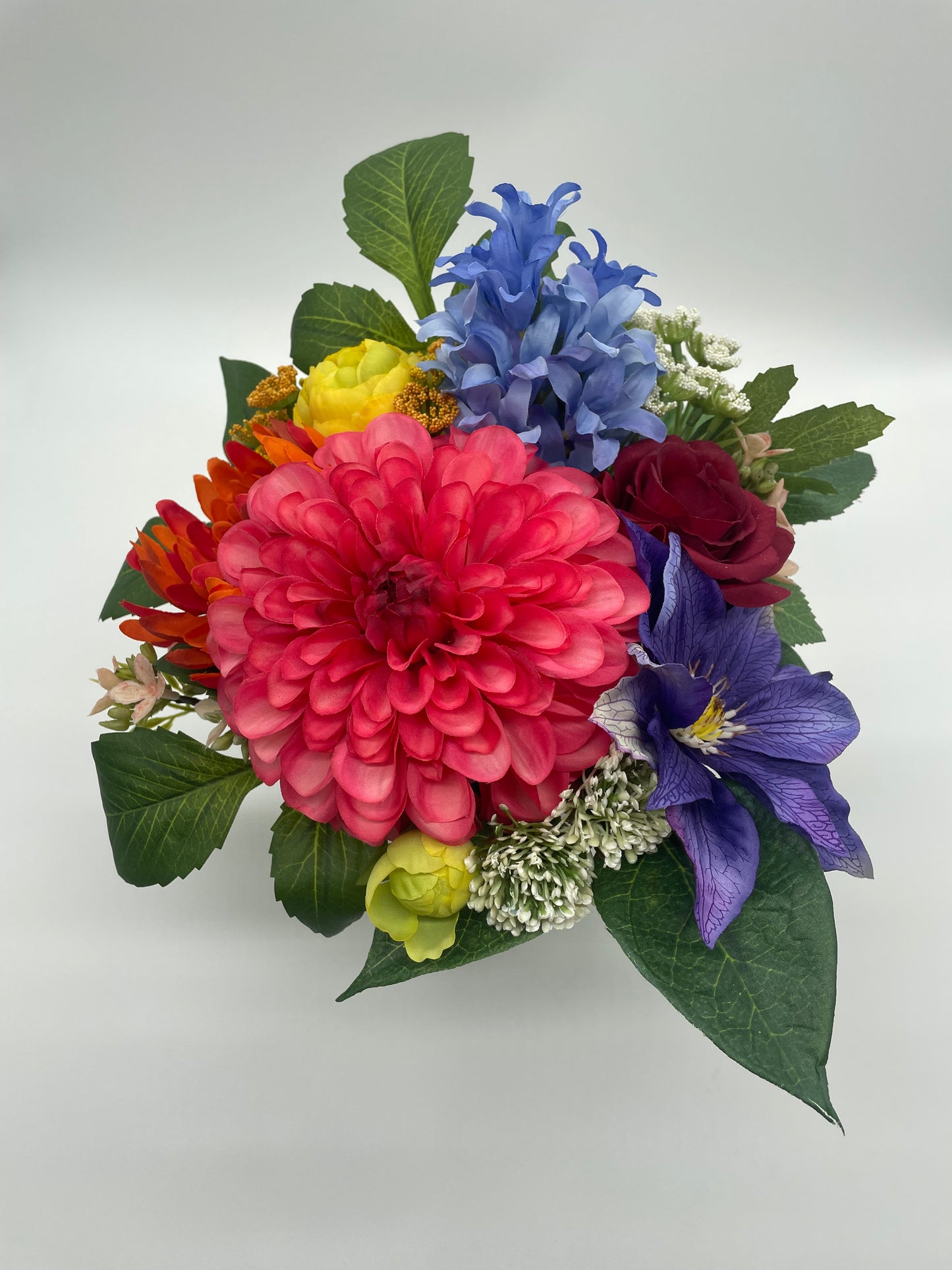 A colorful bouquet featuring blooms of the season. Set in a foam base so that you can transfer to your own favorite container. Bouquet is wrapped in a decorative burlap sack ready to gift or simply place in your space. Bouquet can vary depending on available seasonal blooms.  Measures Approximately 9"x 9"x 11"